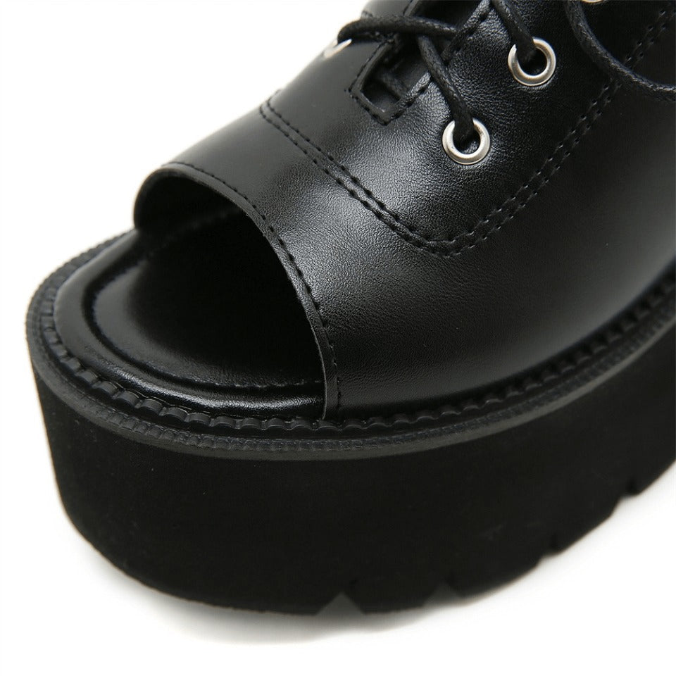 Close-up of stylish black open-toe leather platform sandals for women, featuring lace-up design and gothic flair.