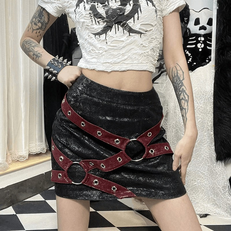 Women's high-waisted mini skirt with rivet straps and rings, styled with a gothic punk aesthetic.