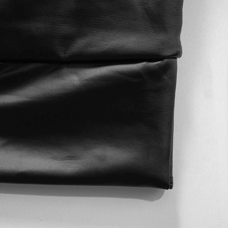 Close-up of a folded women's aesthetic skinny crop top in black fabric texture.