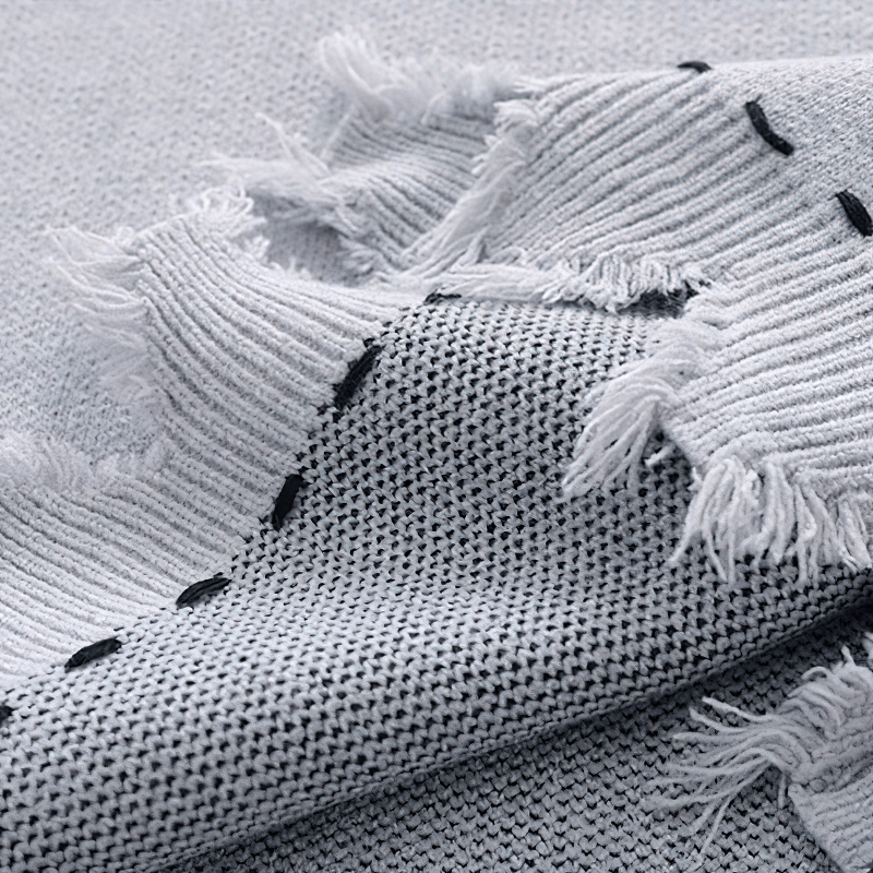 Close-up of soft grey knitted fabric with fringed edges, showcasing the vintage aesthetic and texture of the oversized vest.