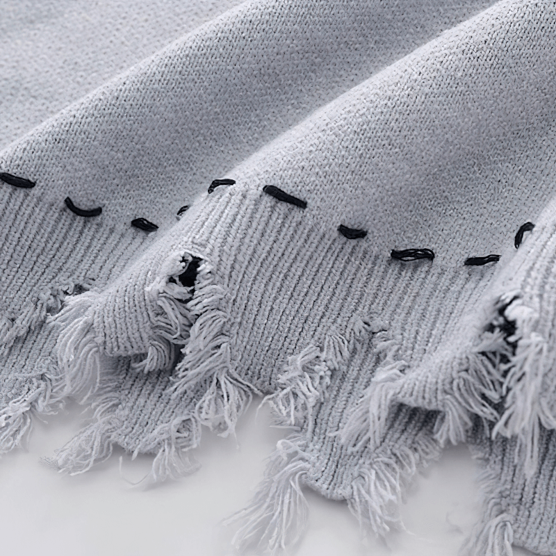 Close-up of a light gray knitted vest with fringed edges, showcasing its soft texture and stylish design.