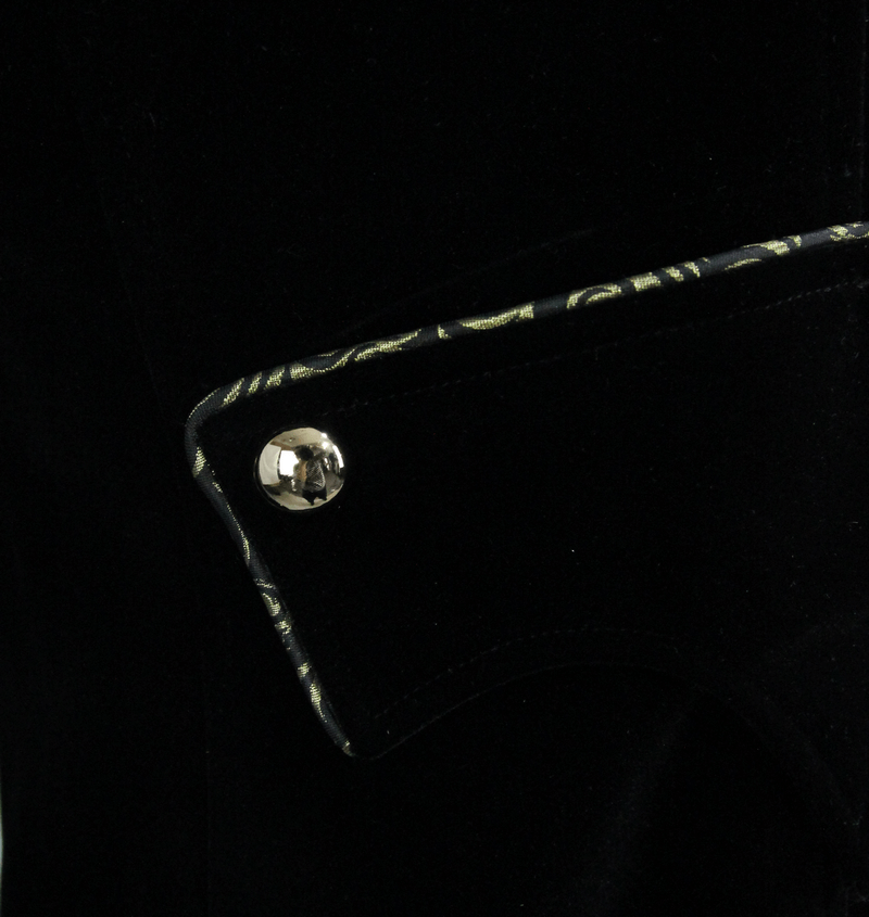 Close-up of vintage black velvet coat with golden embroidery detail and stylish silver button.