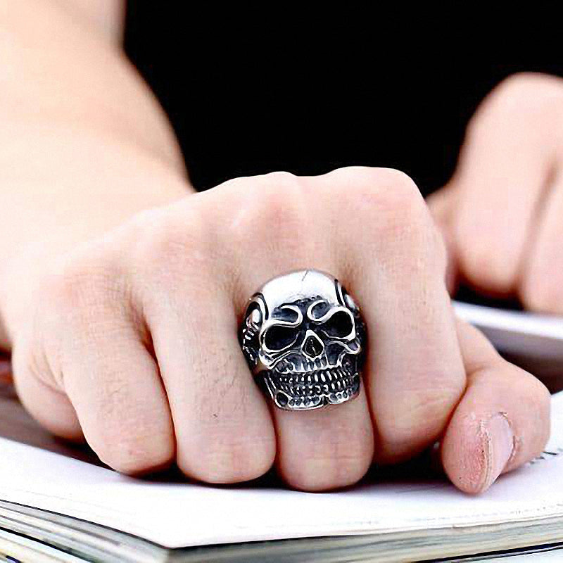 Wearing a big triple skull ring on a hand, showcasing rock style stainless steel biker jewelry.