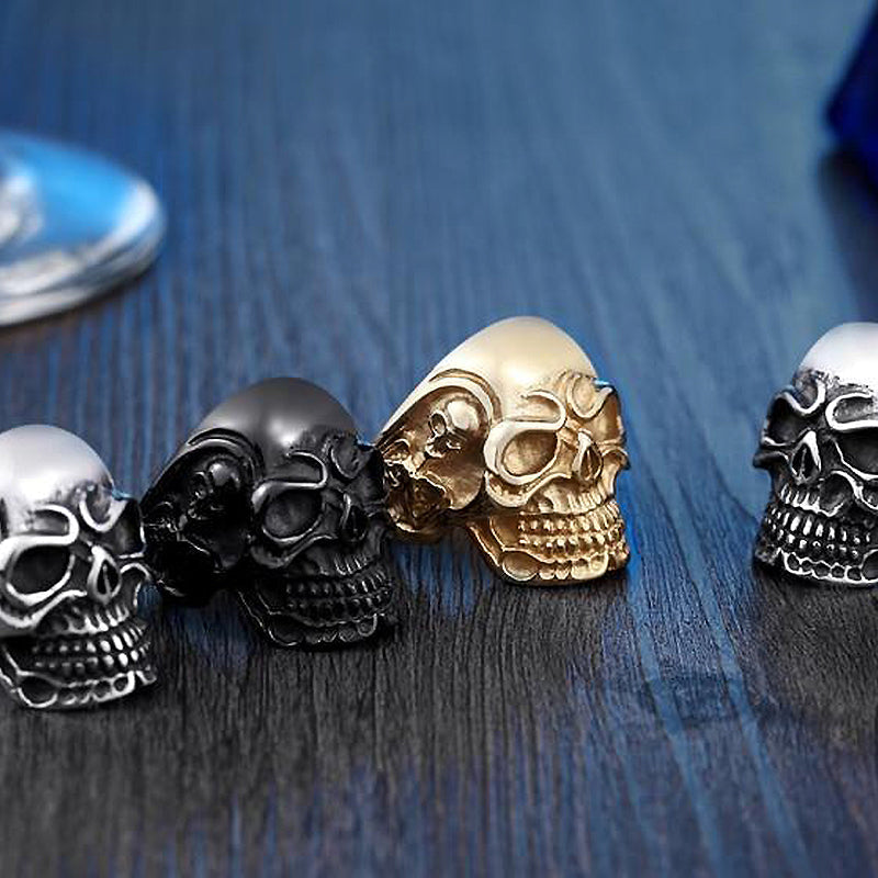 Alternative fashion big triple skull ring with silver, black, and gold designs on a wooden surface.