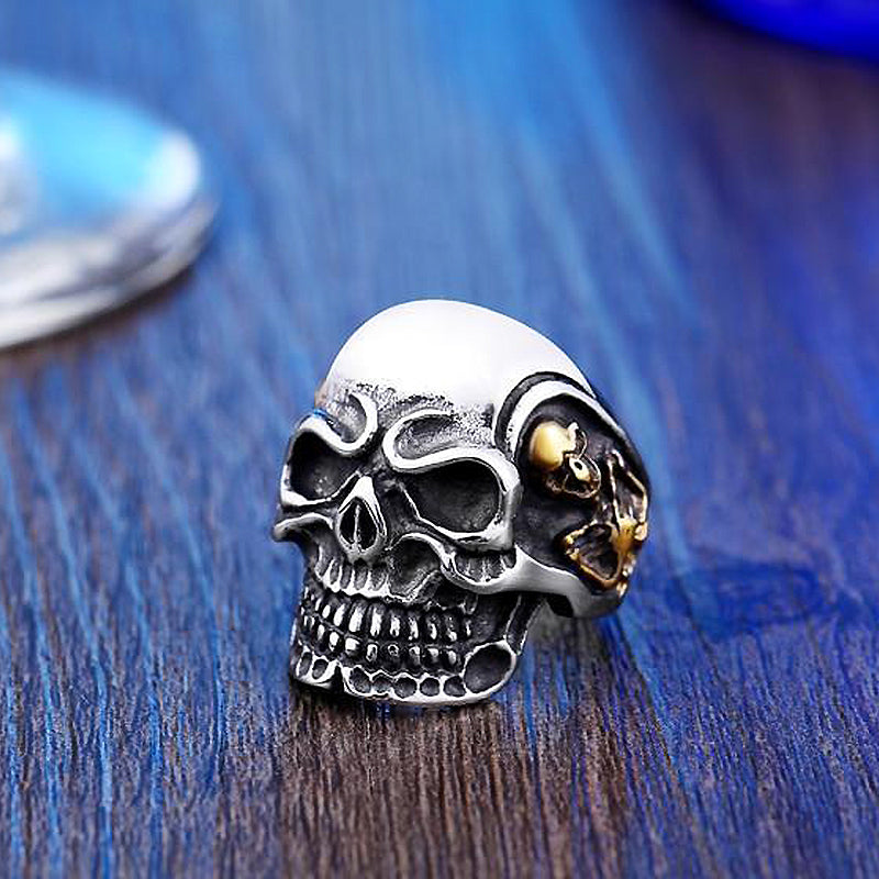 Big triple skull ring shining on wooden surface; stylish biker jewelry with unique design.