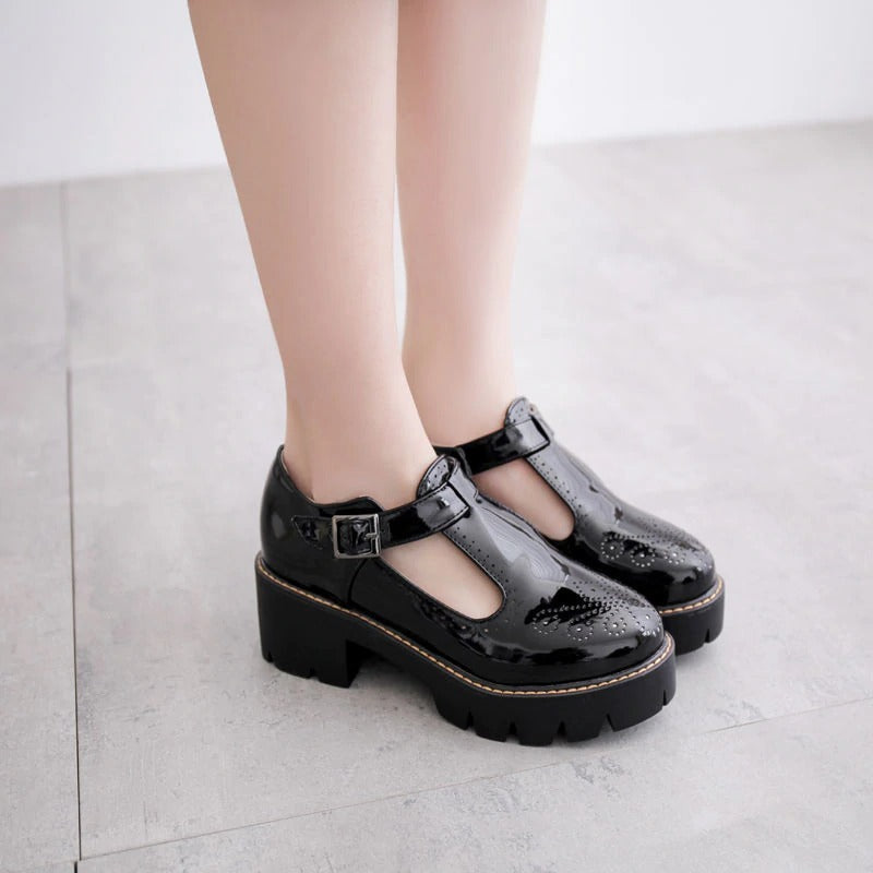 Women's black brogue flats with buckle strap, featuring round toe and chunky heel for a stylish, alternative fashion look.