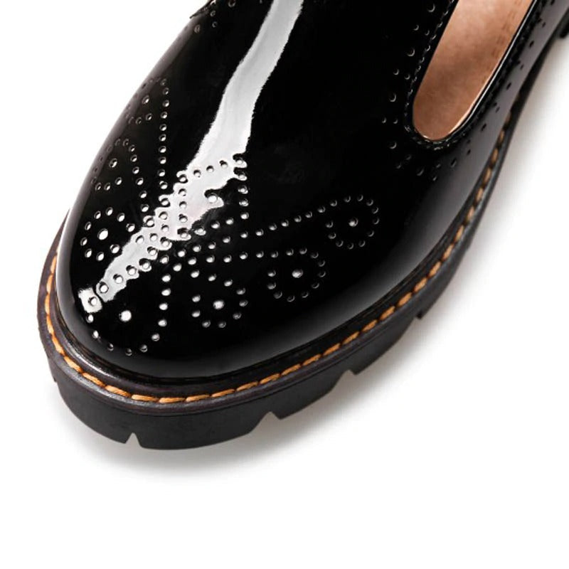 Close-up of black brogue round toe flats with decorative perforations and a flat sole, perfect for an alternative fashion look.