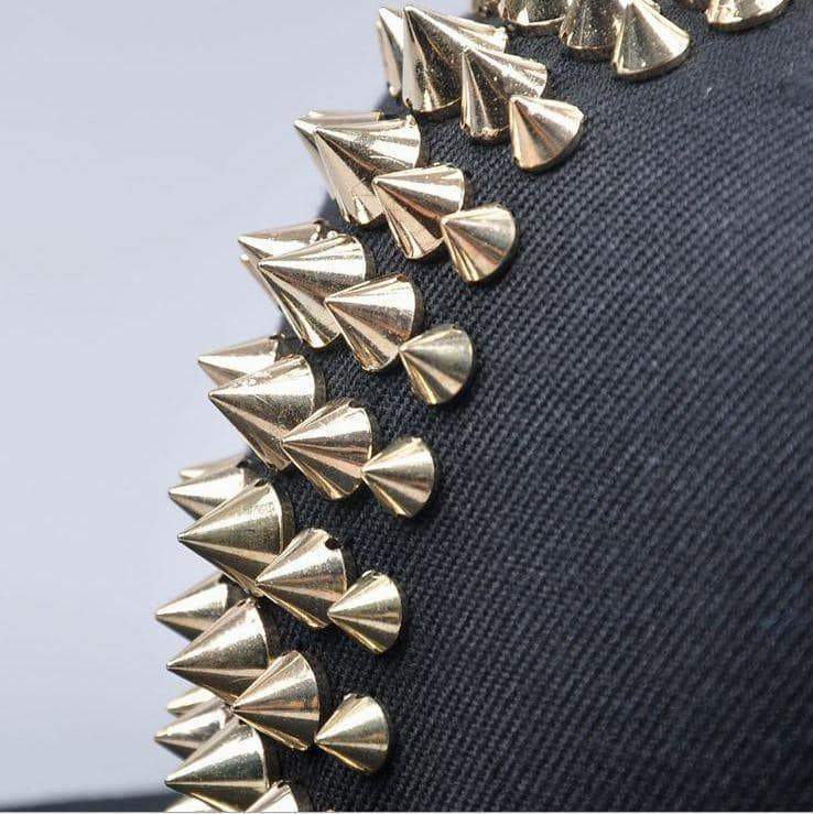 Close-up of gold spike studs on a black baseball cap, showcasing punk rock style and alternative fashion.