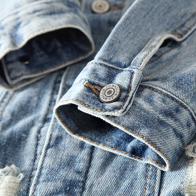 Close-up of alternative streetwear men's denim jacket cuff with stylish button details and distressed fabric.