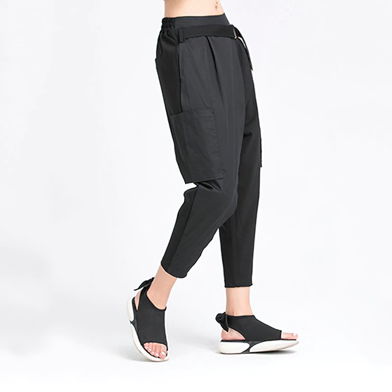 Model wears loose fit black trousers with high elastic waist, styled with trendy sandals for an alternative fashion look.