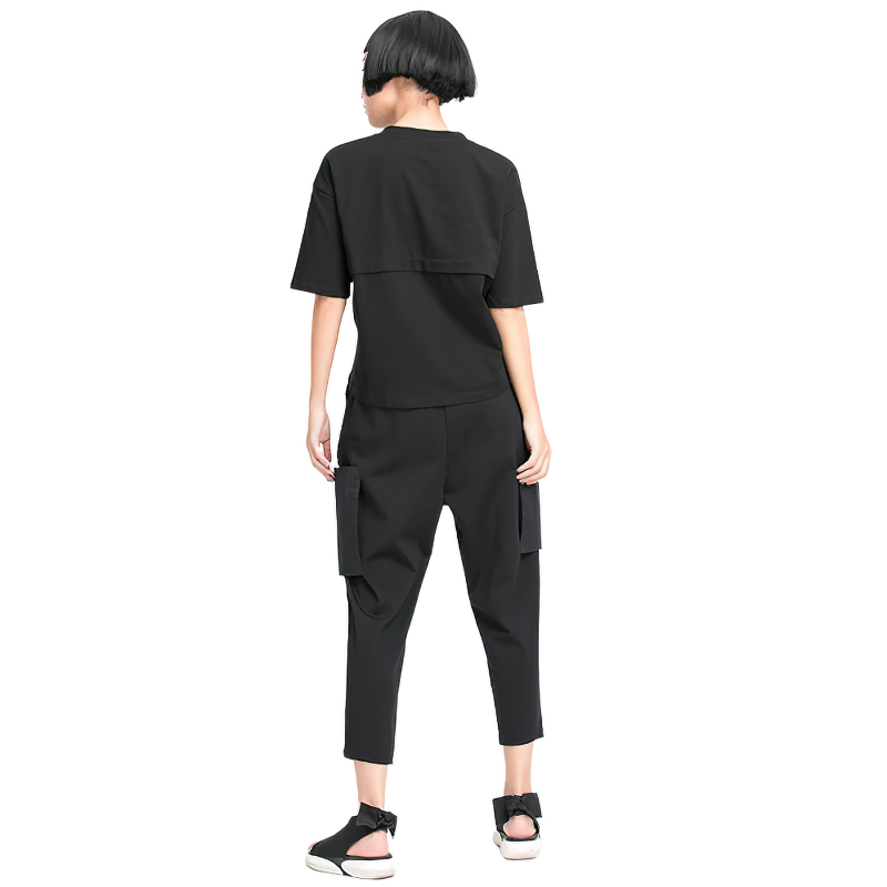 Back view of a model wearing loose fit black trousers and a short-sleeve top, showcasing alternative style fashion.