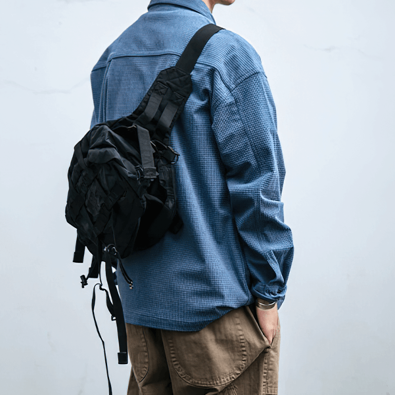 Man wearing a loose blue waffle plaid shirt with a stylish black backpack, showcasing alternative style clothing.