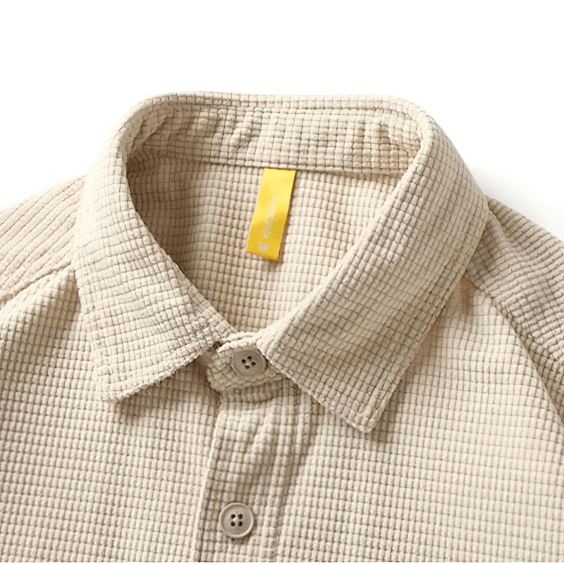 Close-up of a beige waffle plaid shirt collar with buttons, showcasing alternative style men's clothing.