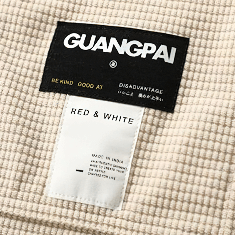 Close-up of GUANGPAI label on red and white waffle plaid shirt, featuring care instructions and branding.
