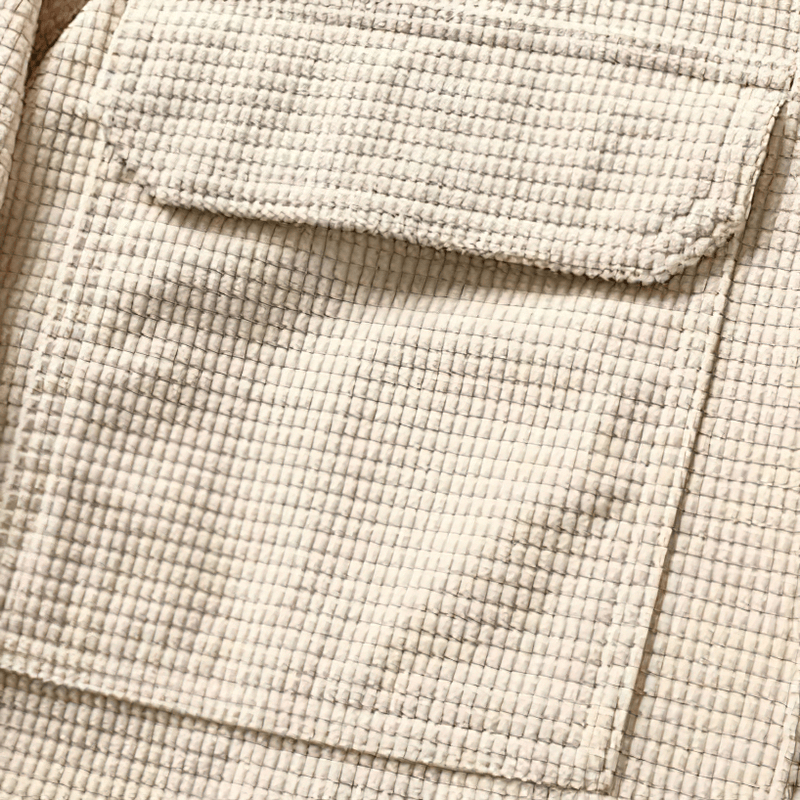 Close-up of textured beige waffle plaid fabric showing pocket details, ideal for stylish loose men's shirts.