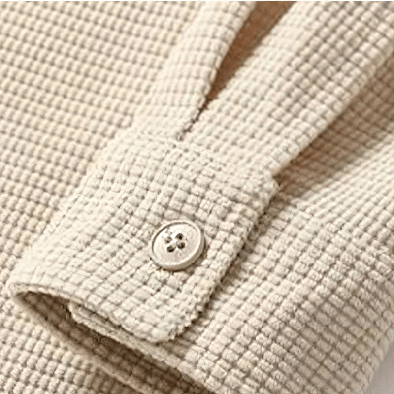 Close-up of a beige waffle plaid shirt sleeve with button detail, showcasing quality fabric and alternative style.