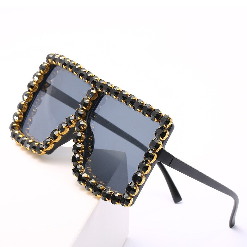 Trendy women's rhinestone sunglasses with bold black frames and gold accents, perfect for alternative fashion.