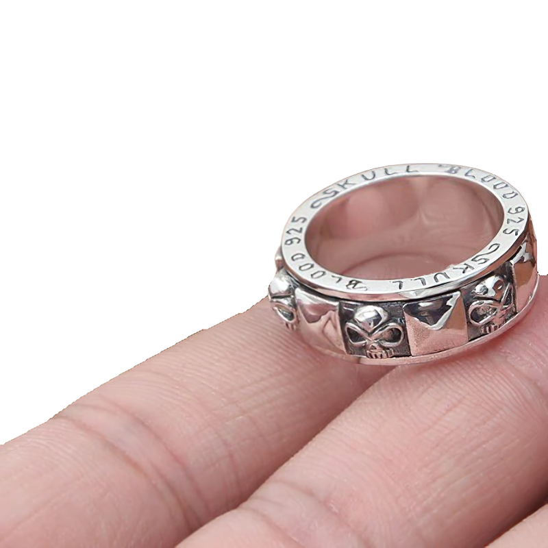Stylish 925 sterling silver skull rotate ring held between fingers, perfect unisex gothic accessory.
