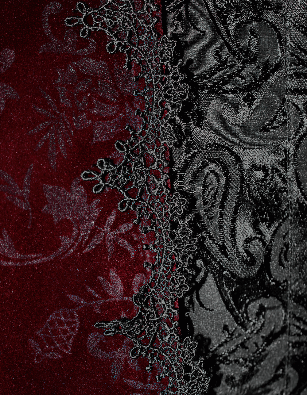Close-up of wine red velvet fabric with intricate black lace detailing, showcasing gothic elegance.