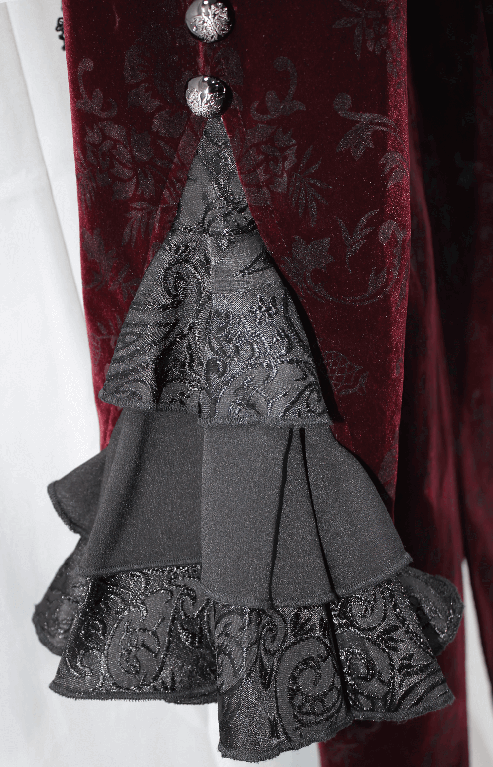 Close-up of the black ruffled detail and elegant buttons on a wine red women's gothic jacket.