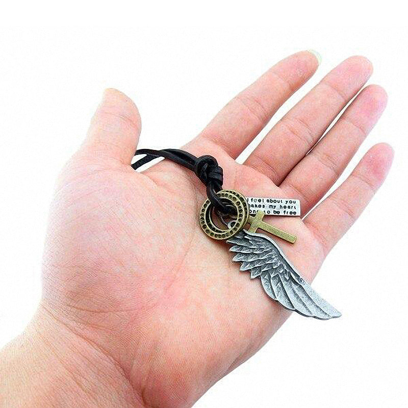 Antique angel wing leather necklace with cross pendant and text charm in a hand, trendy accessory for concerts.