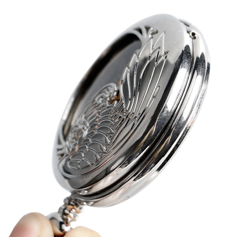 Close-up of antique mechanical pocket watch with engraved wing design and silver finish, perfect for gifts.