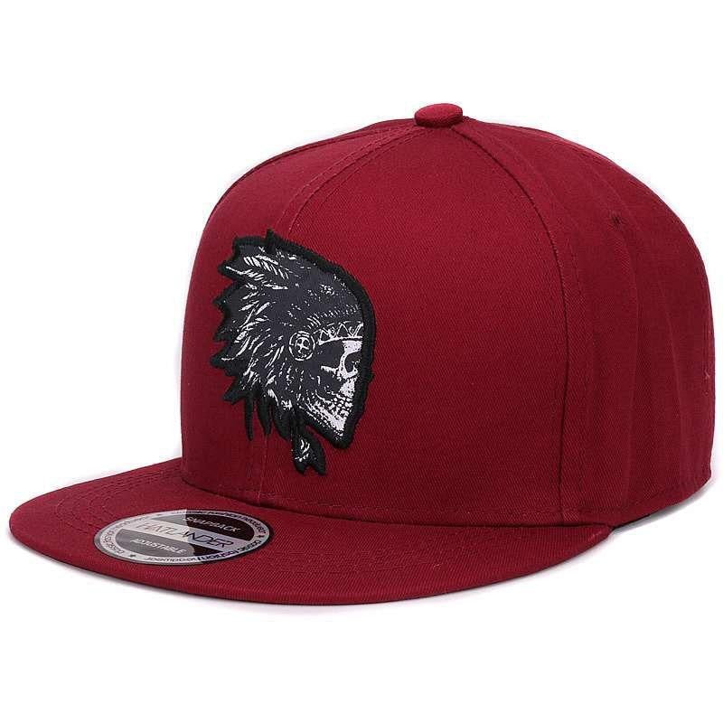 Red snapback cap with embroidered skull design for a bold rock style statement.