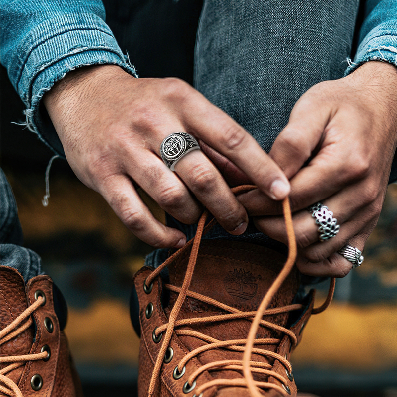 Stylish hands tying shoelaces, showcasing Bear Paw stainless steel rings, Nordic-inspired jewelry for unisex fashion.