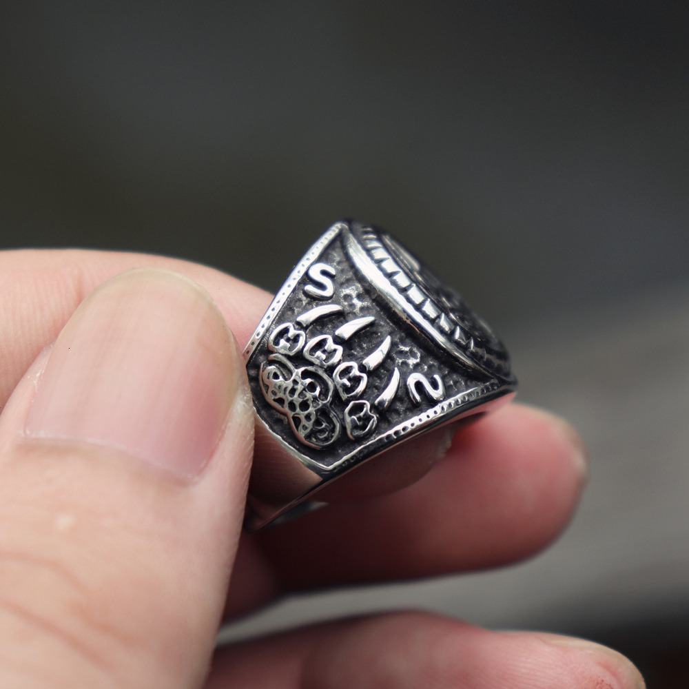 Close-up of a Bear Paw Stainless Steel Talisman Ring, featuring intricate Celtic designs, held in a hand.