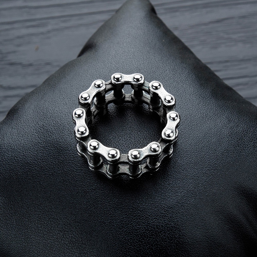 Biker's stainless steel chain ring displayed on black cushion, perfect for punk rock fashion and unisex style.