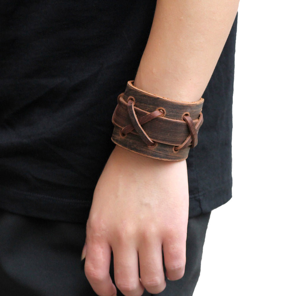 Rock style wide leather bracelet in black and brown, featuring X-type decoration, worn on wrist.
