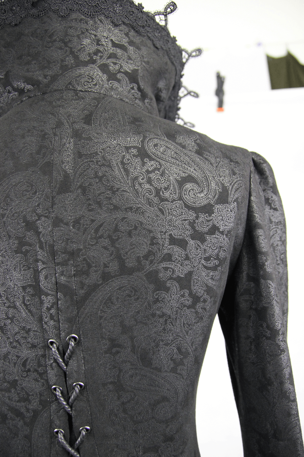 Back view of a black and red embossed Gothic long coat with intricate lacing and elegant paisley pattern.