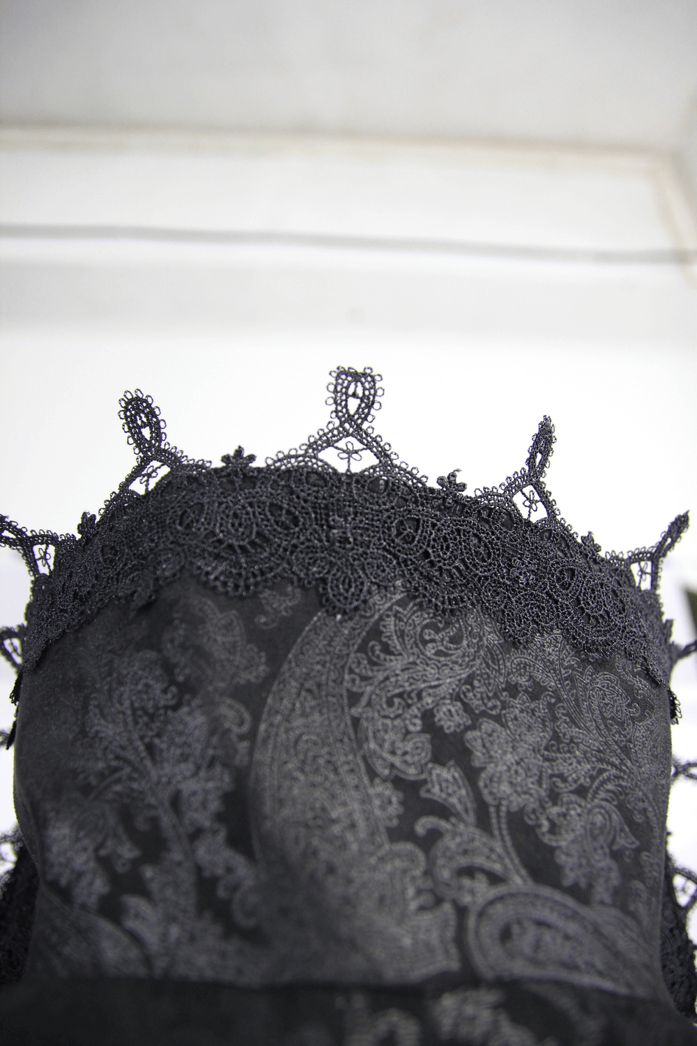 Close-up of intricate black lace detailing on a gothic style garment, showcasing elaborate patterns and textures.