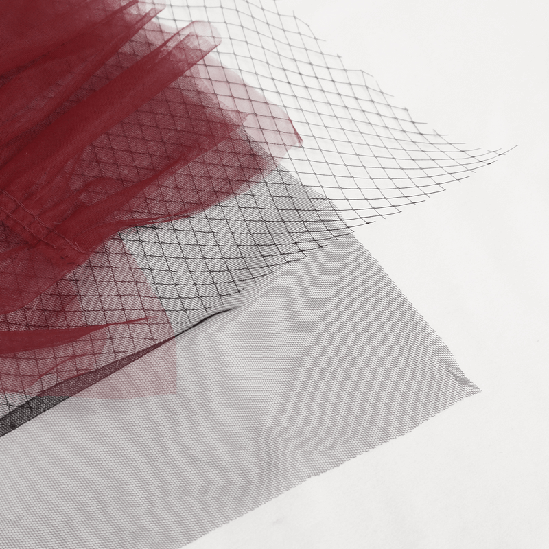 Close-up of black and red mesh fabric layers for gothic skirt design, showcasing stylish textures and patterns.