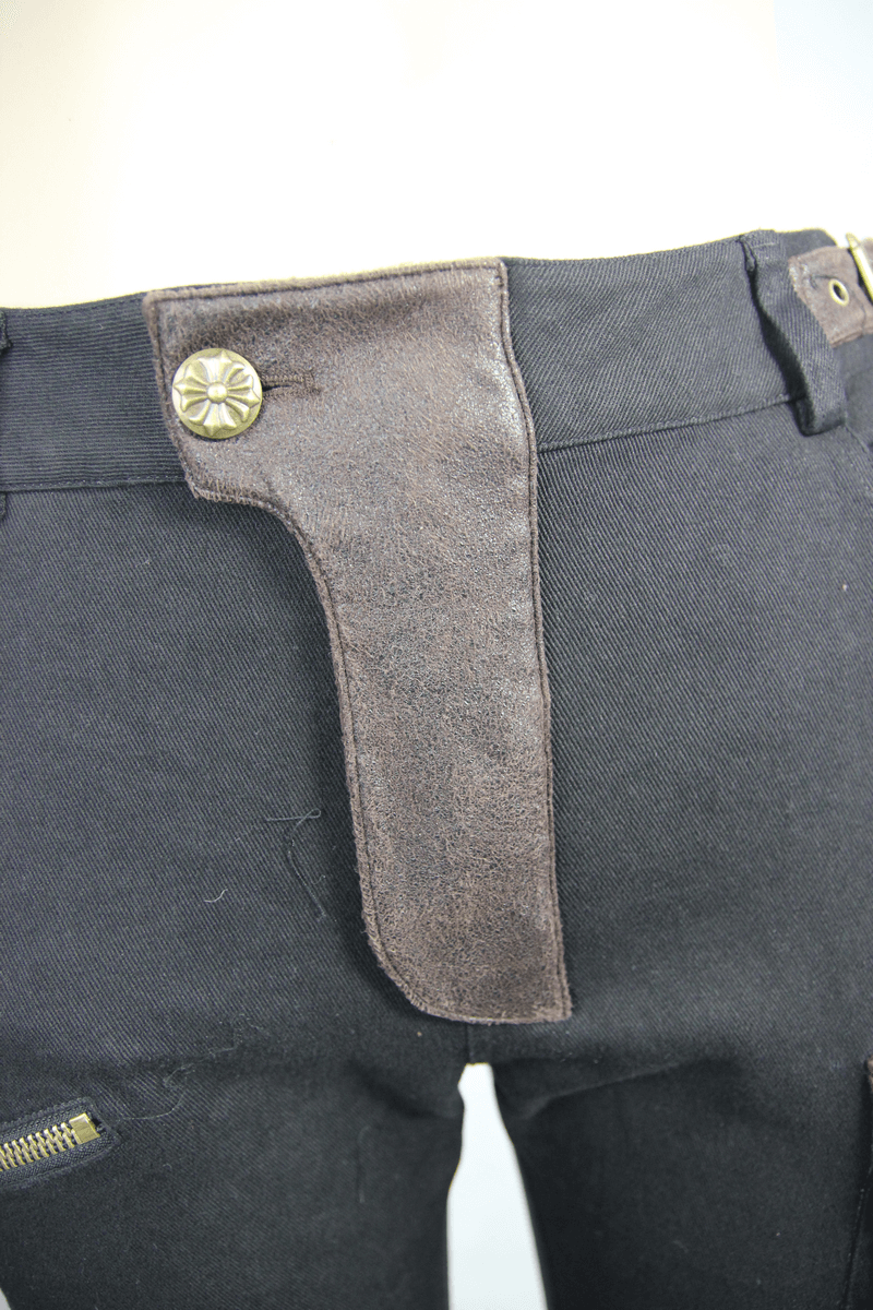Close-up of black steampunk biker trousers with brown leather detailing and stylish button.