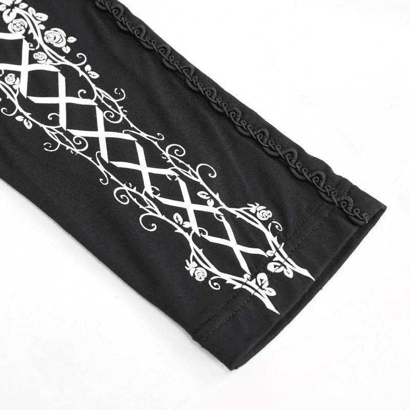 Close-up of stylish black leggings featuring intricate white gothic pattern and elegant lacing detail.