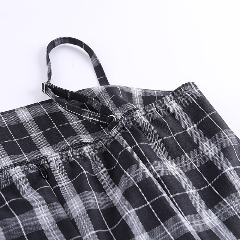 Close-up of black and white plaid fabric on a sleeveless mini dress, featuring adjustable straps and a stylish design.