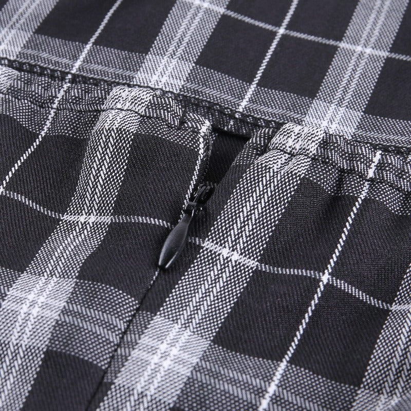 Close-up of black and white plaid fabric with zipper detail for women's sleeveless mini dress.