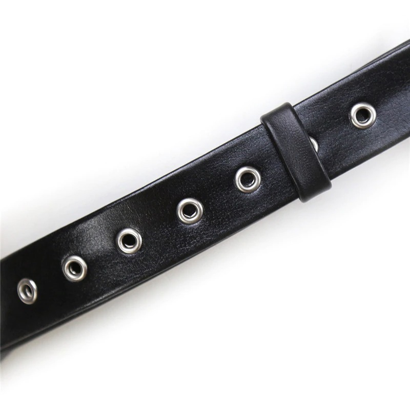Close-up of a black body chest strap harness featuring metallic grommets for adjustable fit and alternative fashion style.