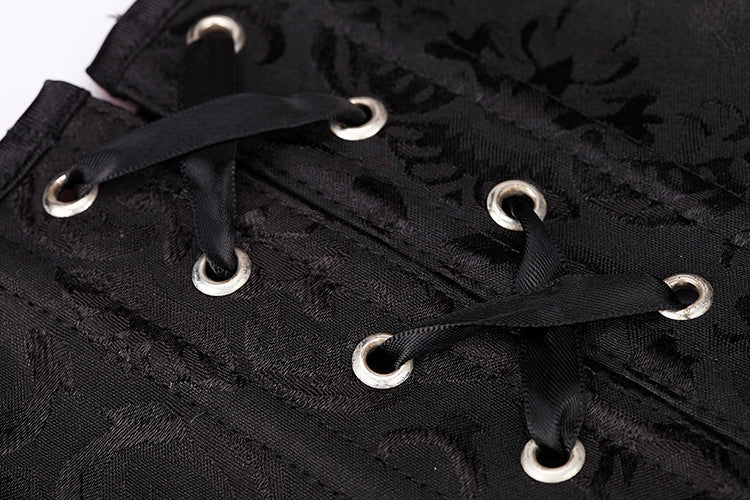 Close-up of black Gothic corset fabric featuring lace decor and belly-closure design with silver grommets.