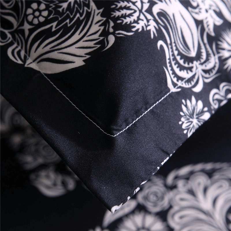 Close-up of a black duvet cover with intricate white floral patterns, showcasing gothic style and elegance.