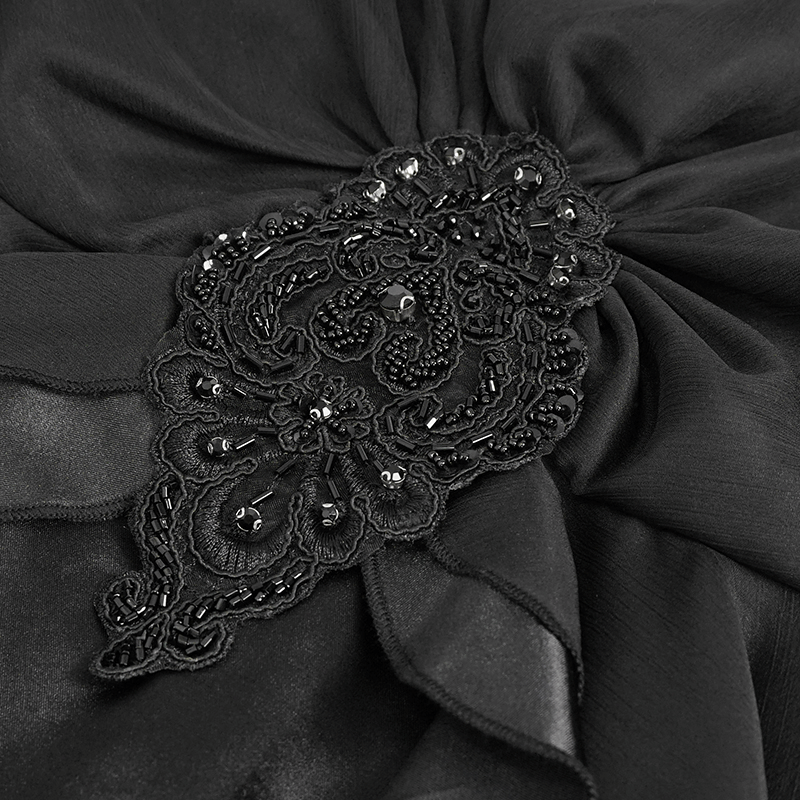 Close-up of intricate black appliqué detailing on elegant retro long dress fabric.