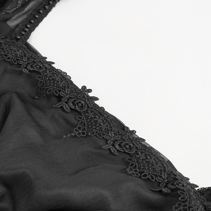 Close-up of black elegant retro dress featuring delicate lace appliqué and sophisticated detailing.