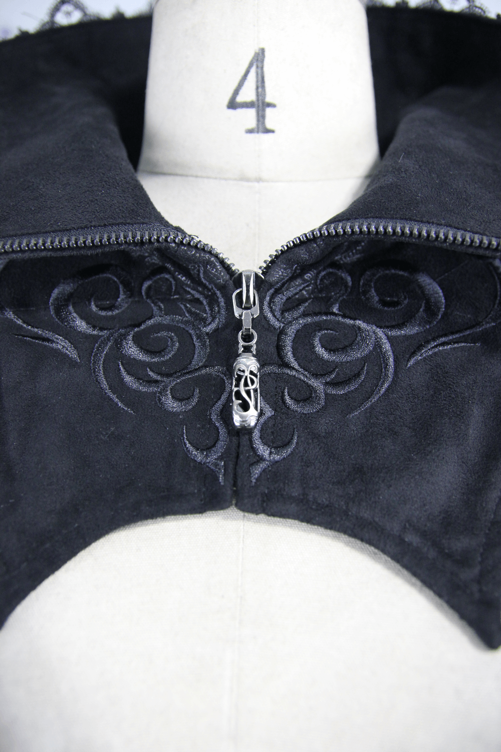 Close-up of the embossed detailing on a black Gothic long coat, featuring a sexy high collar and intricate zipper.