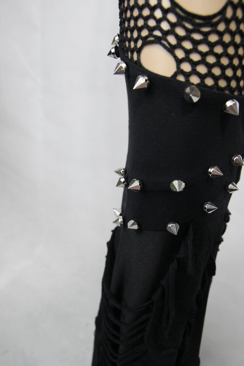 Close-up of black flared pants showing torn mesh and studded details, perfect for gothic fashion styling.