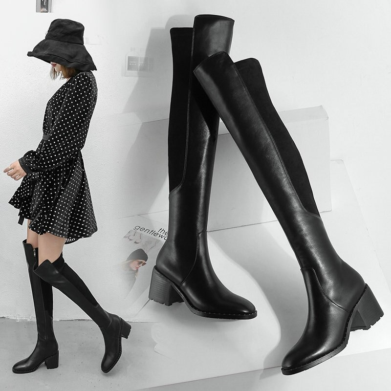 Stylish black knee-high leather boots with round toe, worn with a polka dot dress and hat for a chic look.
