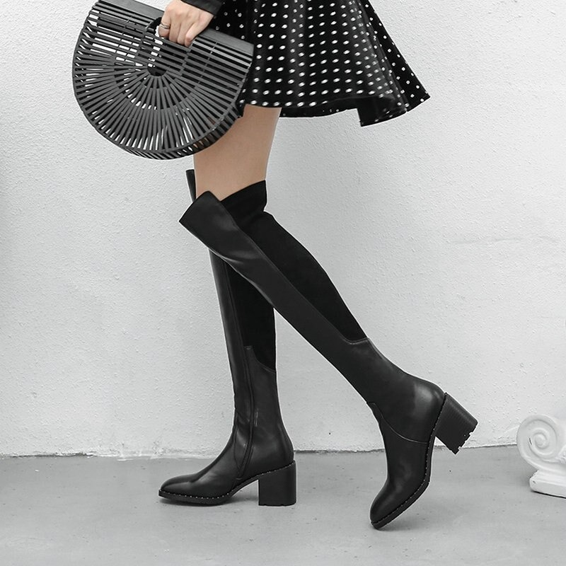 Black genuine leather knee-high boots with block heels and a stylish round toe, paired with a polka dot skirt.