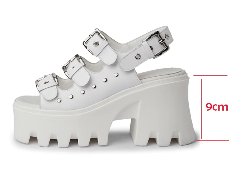 White platform sandals with buckles and rivets, featuring a chunky heel and punk-inspired design.