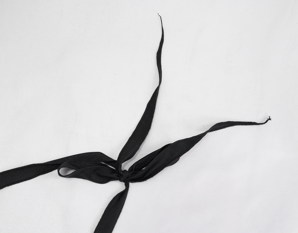 Black lace-up ribbon tied in a bow, perfect accent for gothic and beach wear fashion.