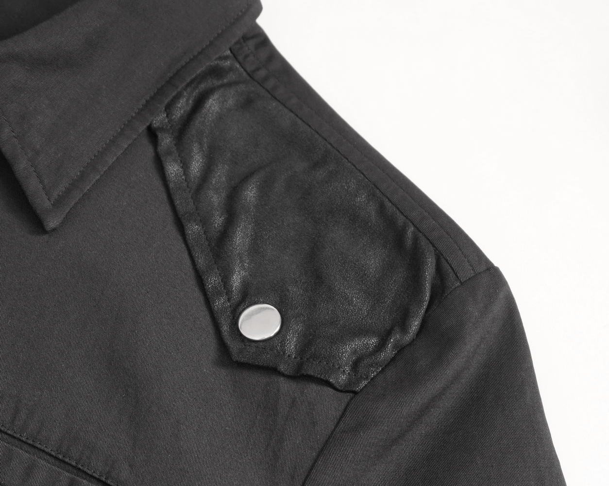 Close-up of men's black gothic punk shirt shoulder with imitation leather detail and snap button.